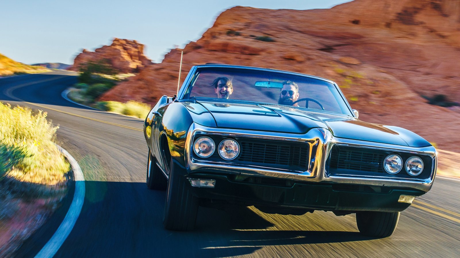 couple driving together in cool vintage car through desert