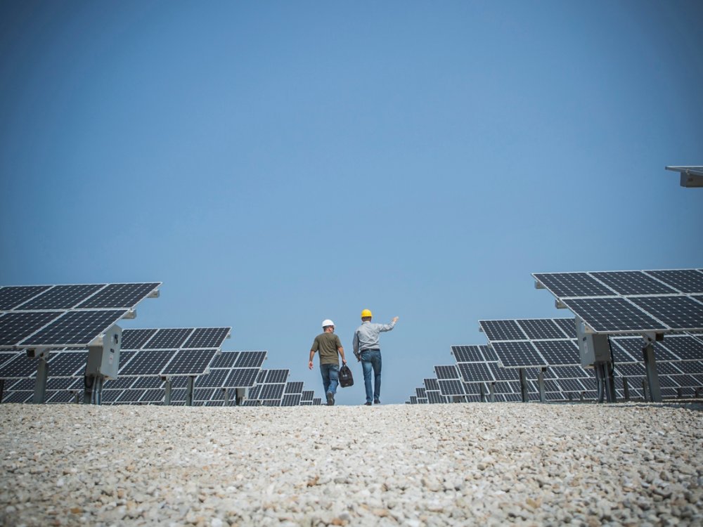 Caucasian technicians talking near solar panels