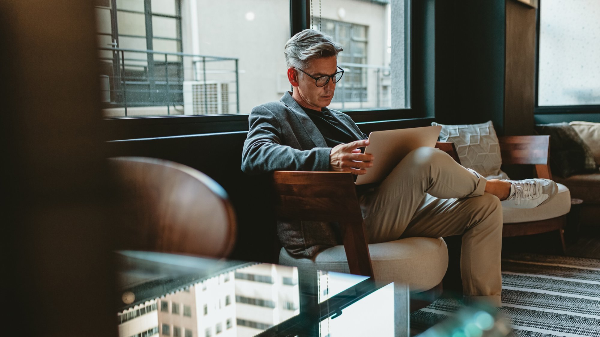 Mature businessman sitting in office lobby with a laptop. Male executive working in office lounge.