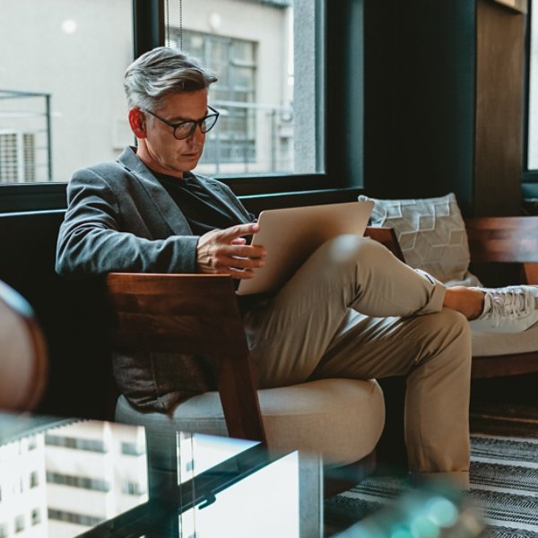 Mature businessman sitting in office lobby with a laptop. Male executive working in office lounge.