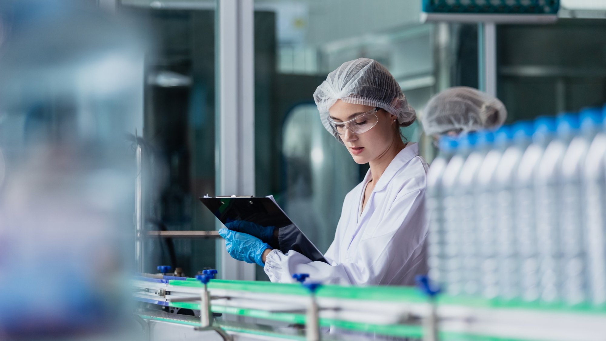 Woman factory worker manufacturing water bottles in a sterile environment by leveraging BaaS services