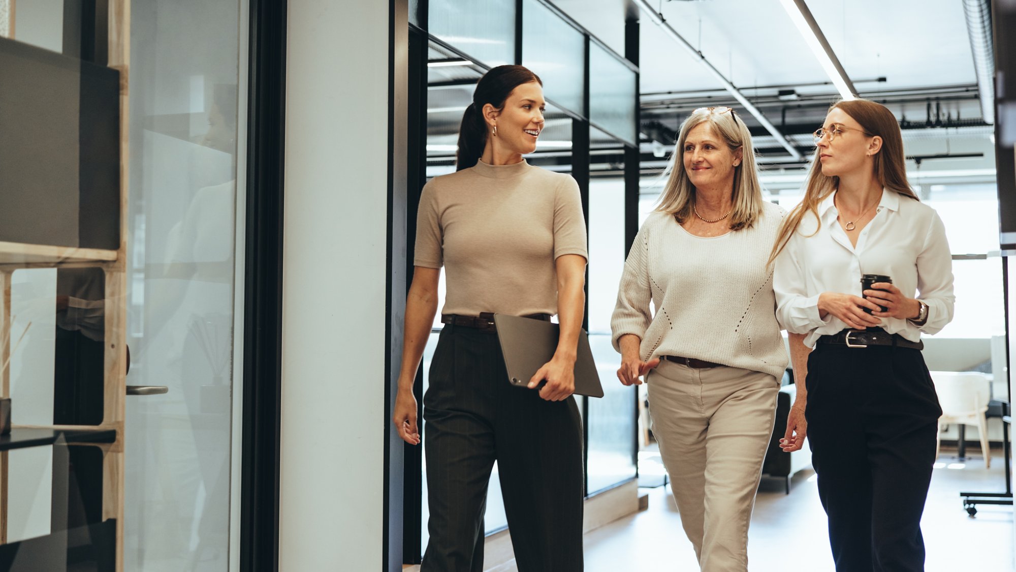 Three cheerful businesswomen walking together in an office. Diverse group of businesswomen smiling while having a discussion. Successful female colleagues collaborating on a new project.