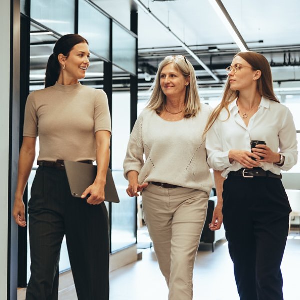 Three cheerful businesswomen walking together in an office. Diverse group of businesswomen smiling while having a discussion. Successful female colleagues collaborating on a new project.