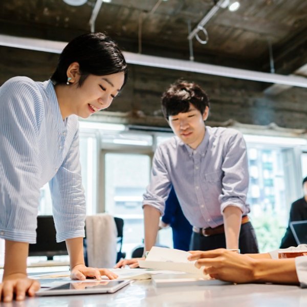 A group of multi-ethnic young business people are talking to each other in a modern working space in Tokyo.