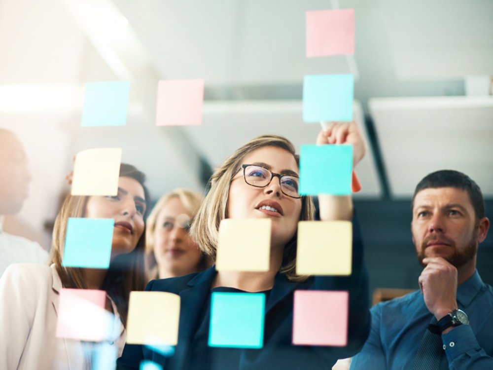 Planning, innovation and vision business meeting in a modern office, working on a business marketing strategy. Group, team or staff discussing with sticky notes a schedule for future project together.