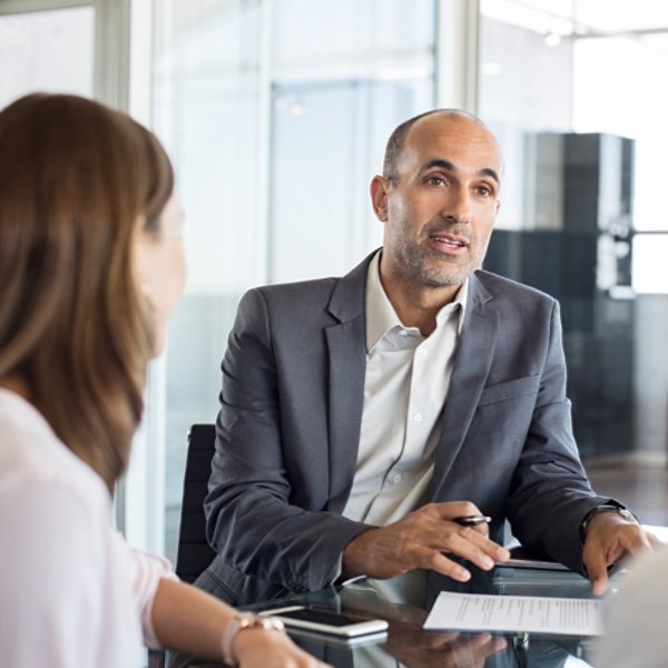 Mature financial agent showing new investment to young couple. Happy financial advisor discussing with a couple their mortgage loan. Happy couple consulting their bank agent about savings plan.