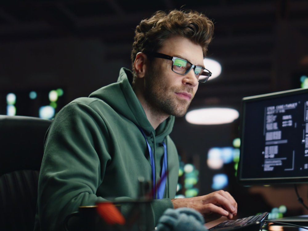 Datacenter analyst looking monitors in advanced monitoring office closeup. Professional software engineer typing keyboard working at computer. IT engineer in glasses monitoring data at server room