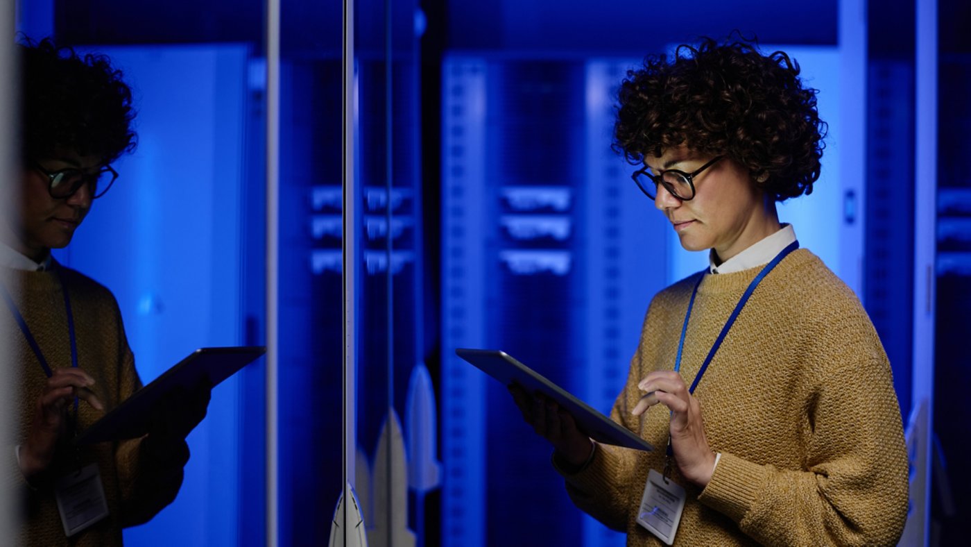 Female technician using digital tablet examining in server room