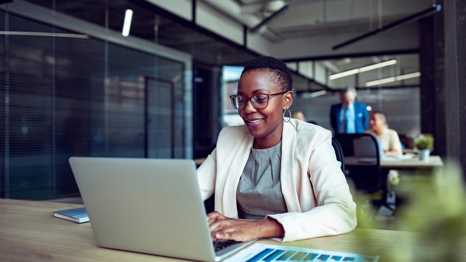 Smiling businesswoman working on laptop in office