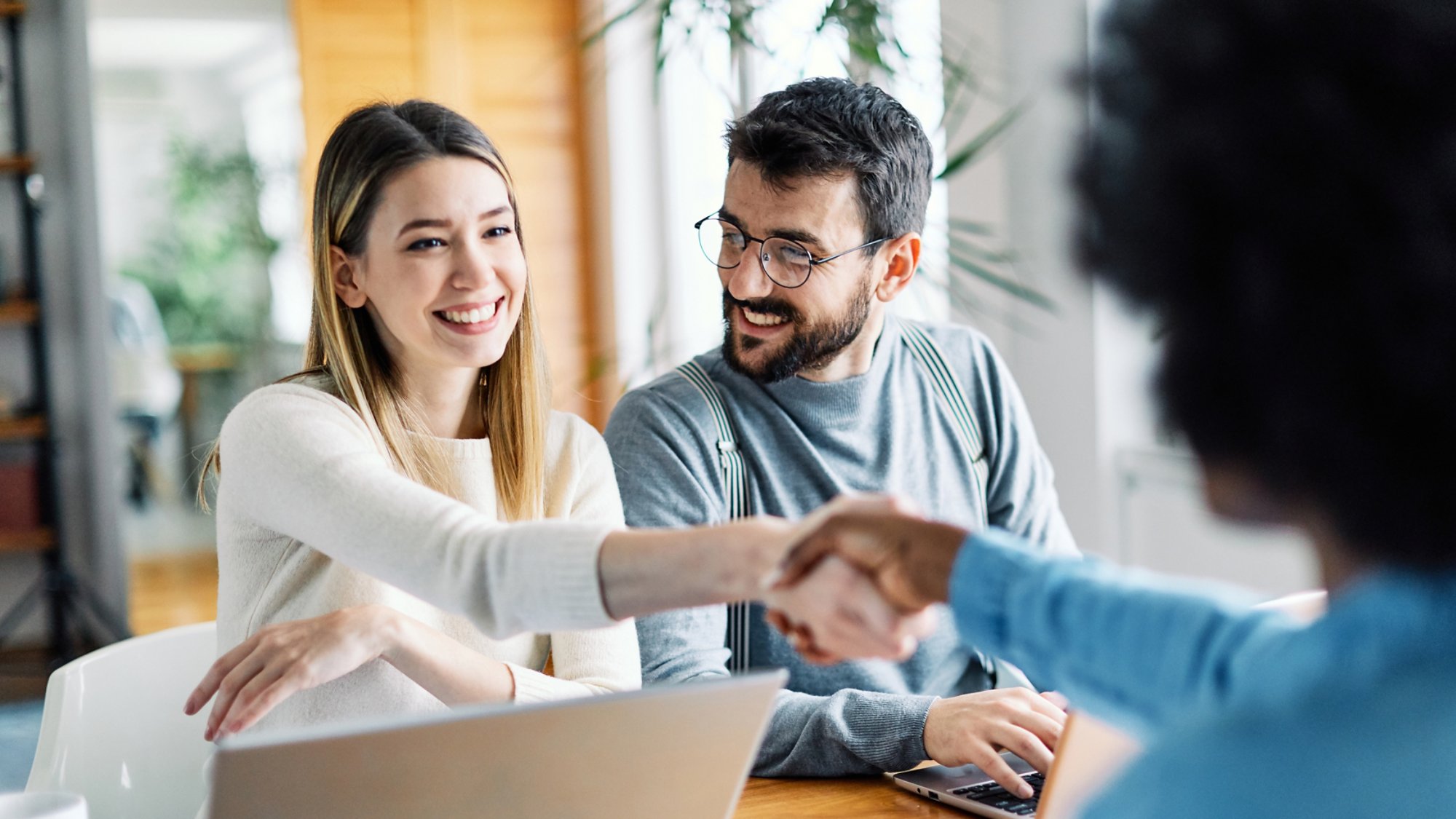 Real estate agent with couple shaking hands closing a deal