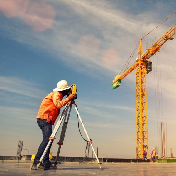 Surveyor builder Engineer with theodolite transit equipment at construction site outdoors during surveying work