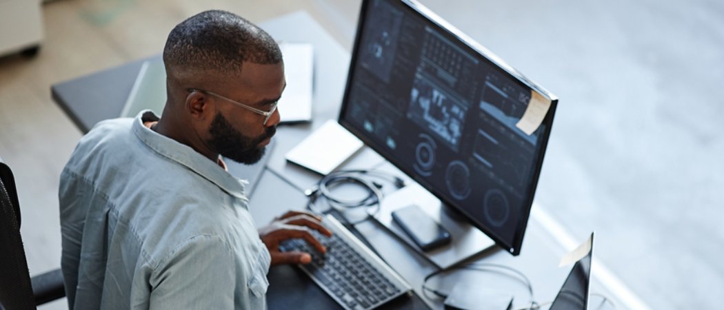 Minimal high angle view at African American software developer working with computers and data systems in office