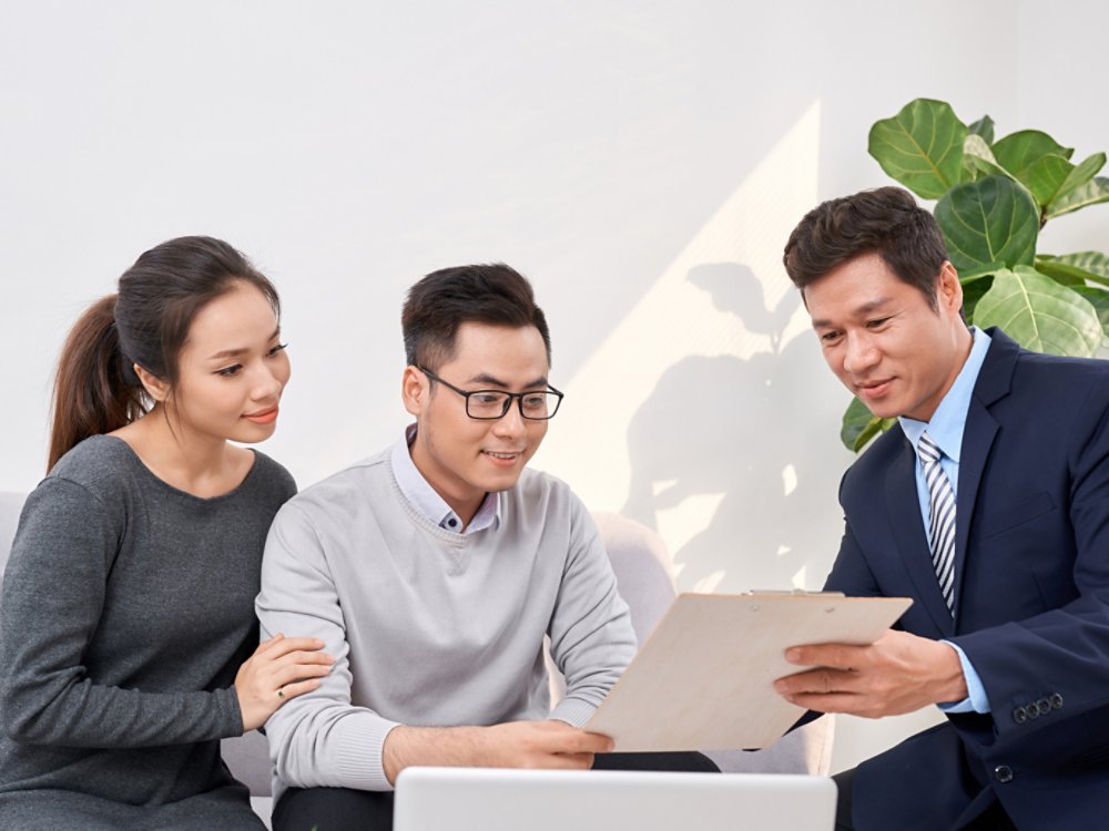 Sales Consultant showing new investment plans to young asian couple