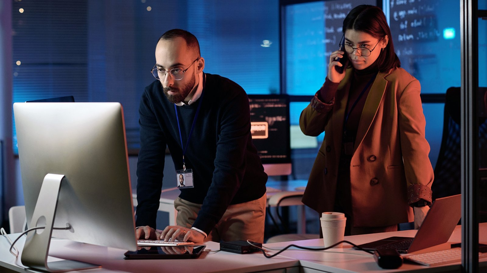 Portrait of two people working in cybersecurity department with red neon light critical emergency situation