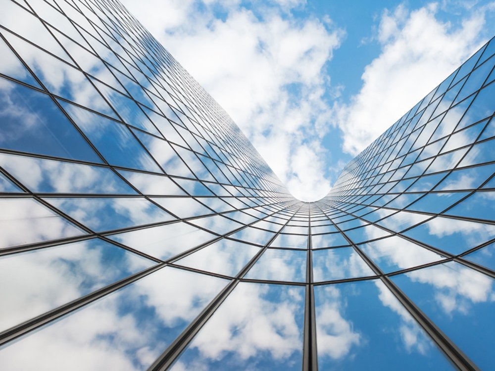 Blue sky and white clouds reflecting in a curved glass building