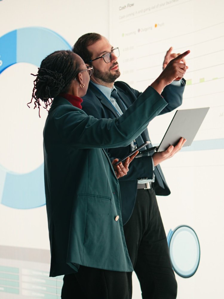 Corporate managers evaluate fiscal performance metrics on digital wall, collaborating, Diverse executive team discusses quarterly earnings report and shareholder equity charts during boardroom.