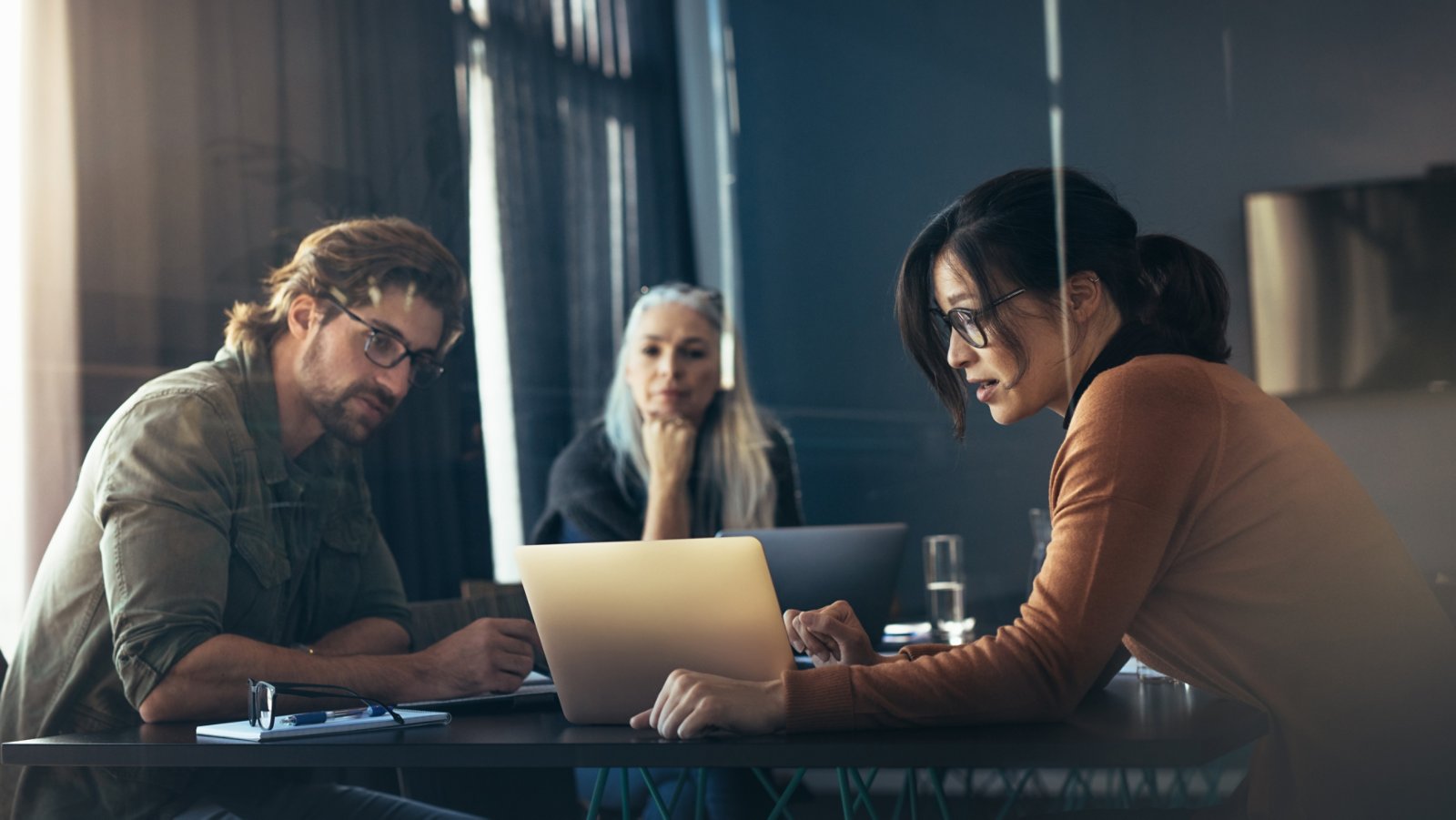 Business woman sharing her ideas with laptop to colleagues. Business people meeting in office and discussing over new project.