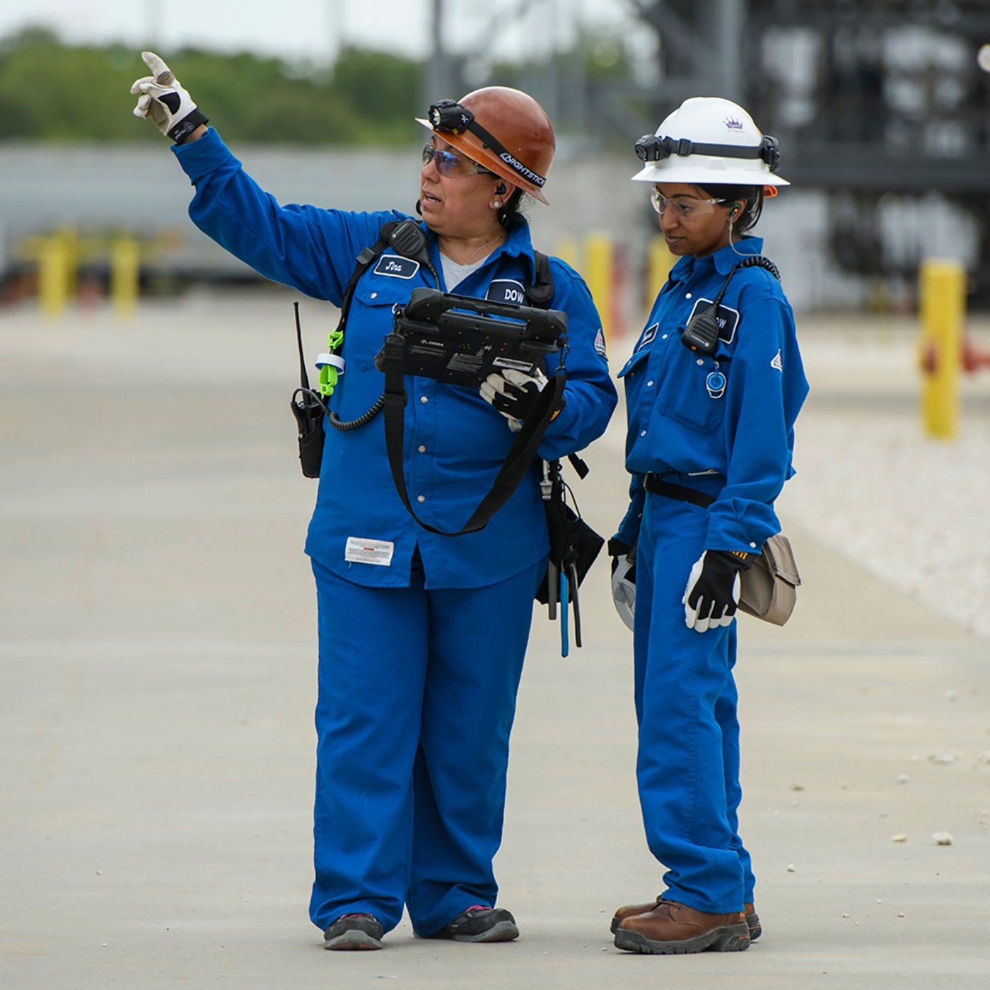 Two workers from DOW checking on their systems via a handheld computing device