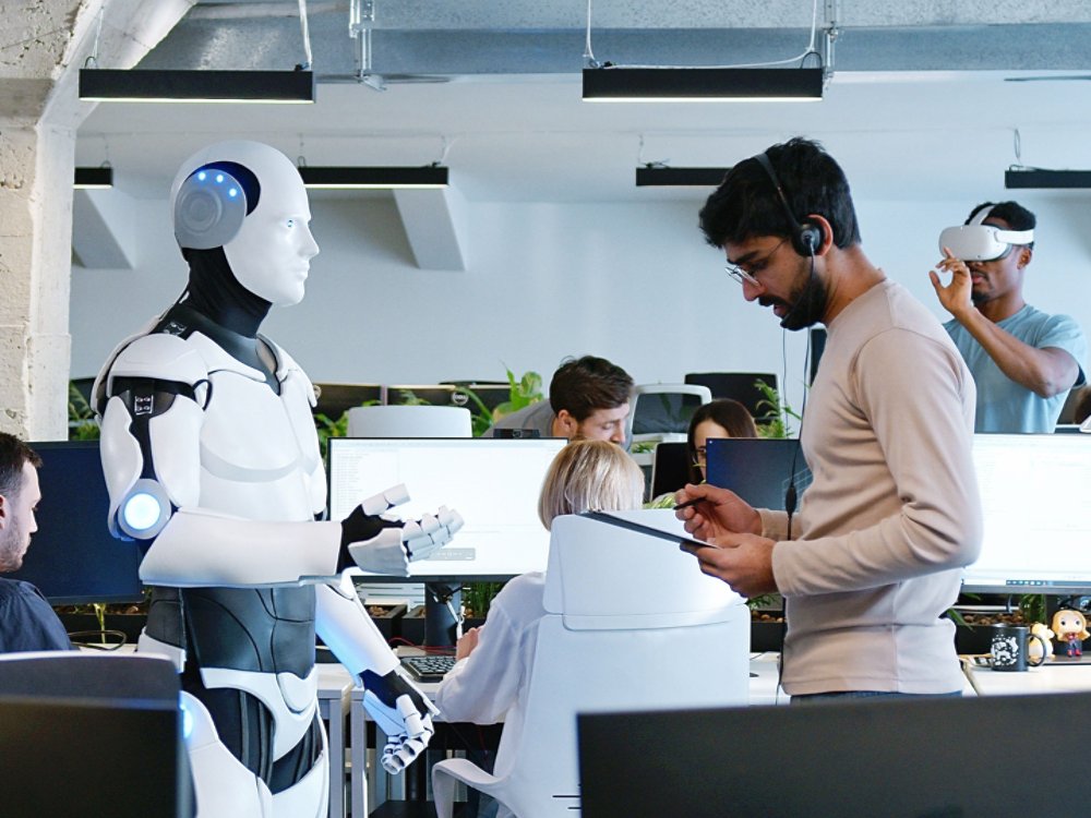 Indian man speaking to robot in office. Male developer checking work and moves of cyborg. Coworking space. Humanoid moving and executing instructions and orders. Artificial intelligence Startup.