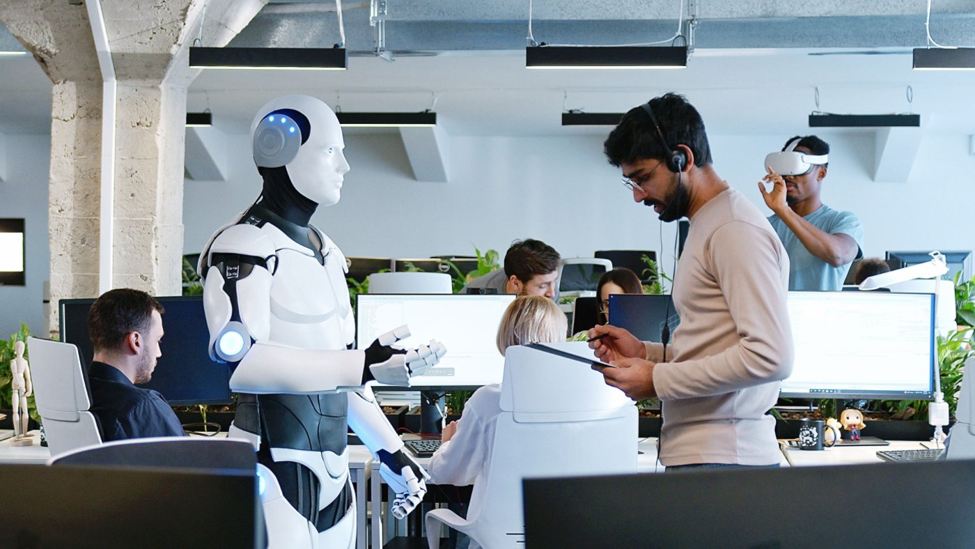 Indian man speaking to robot in office. Male developer checking work and moves of cyborg. Coworking space. Humanoid moving and executing instructions and orders. Artificial intelligence Startup.