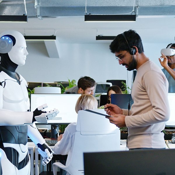 Indian man speaking to robot in office. Male developer checking work and moves of cyborg. Coworking space. Humanoid moving and executing instructions and orders. Artificial intelligence Startup.