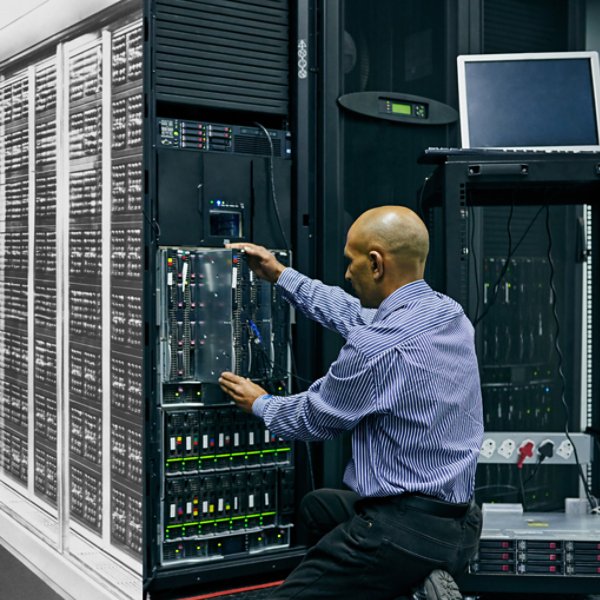 An image depicting an old data warehouse with a man working and a modern mainframe warehouse with a man kneeling. 