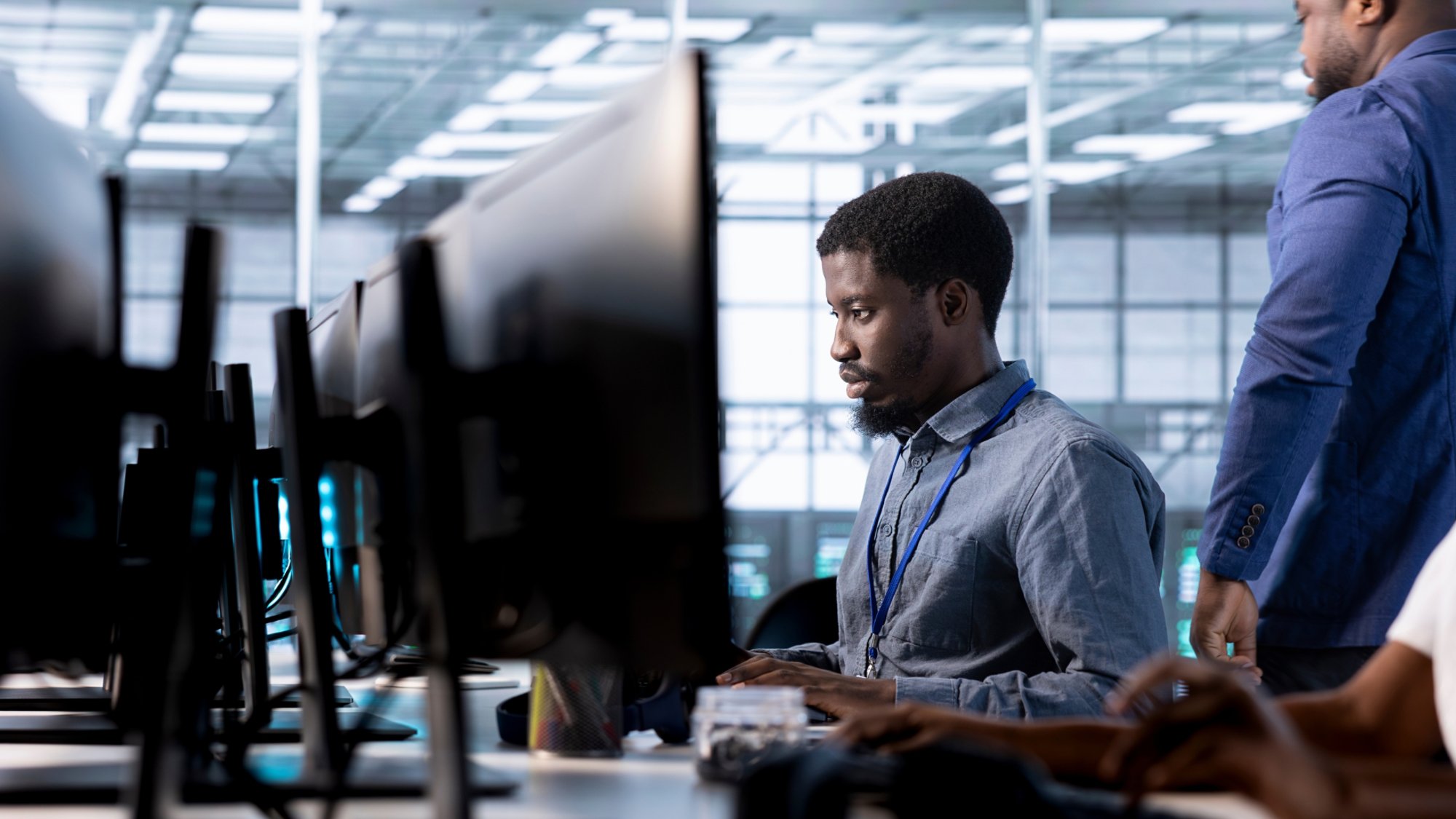 Engineer next to coworkers in server farm checking recovery plan, monitoring data center energy consumption. Employee and colleagues in server room doing routine disk checks