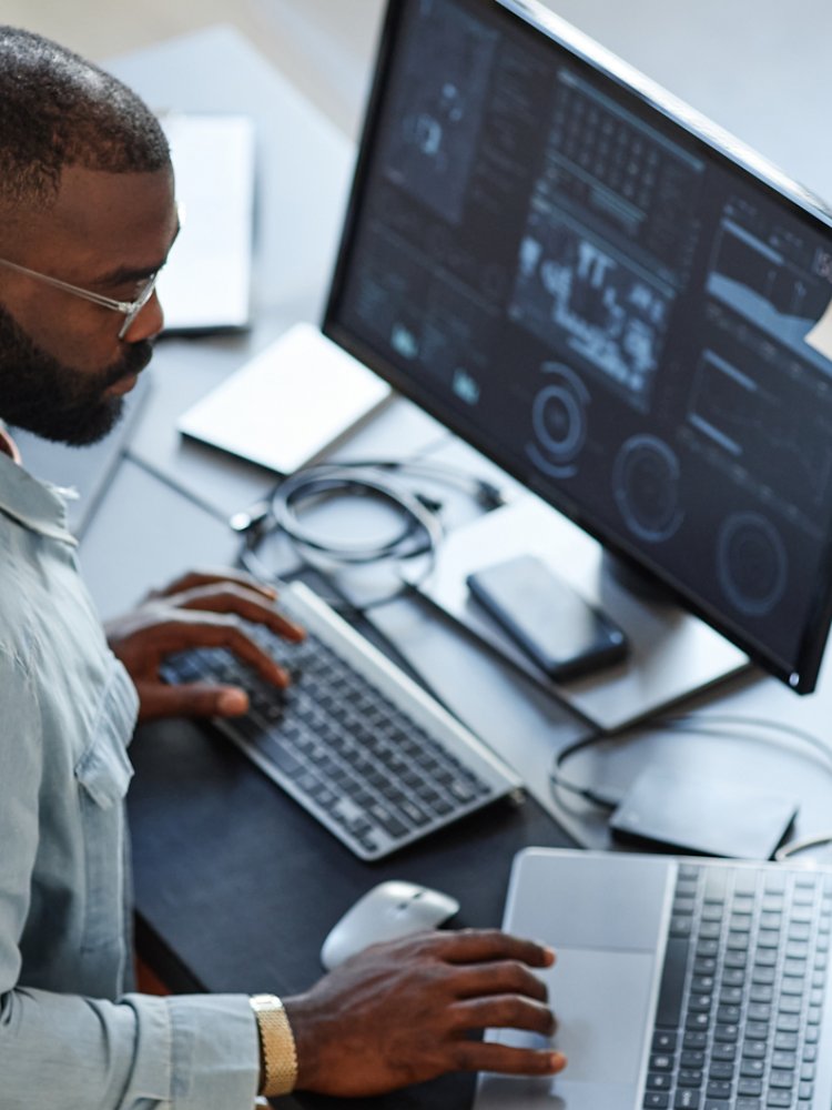 Minimal high angle view at African American software developer working with computers and data systems in office