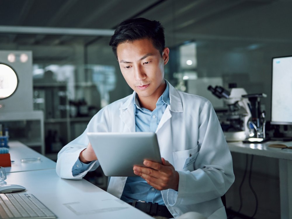 Tablet, planning and scientist with digital innovation, data and reading in laboratory. Asian man, doctor and information technology for futuristic medical research with pharma healthcare study.