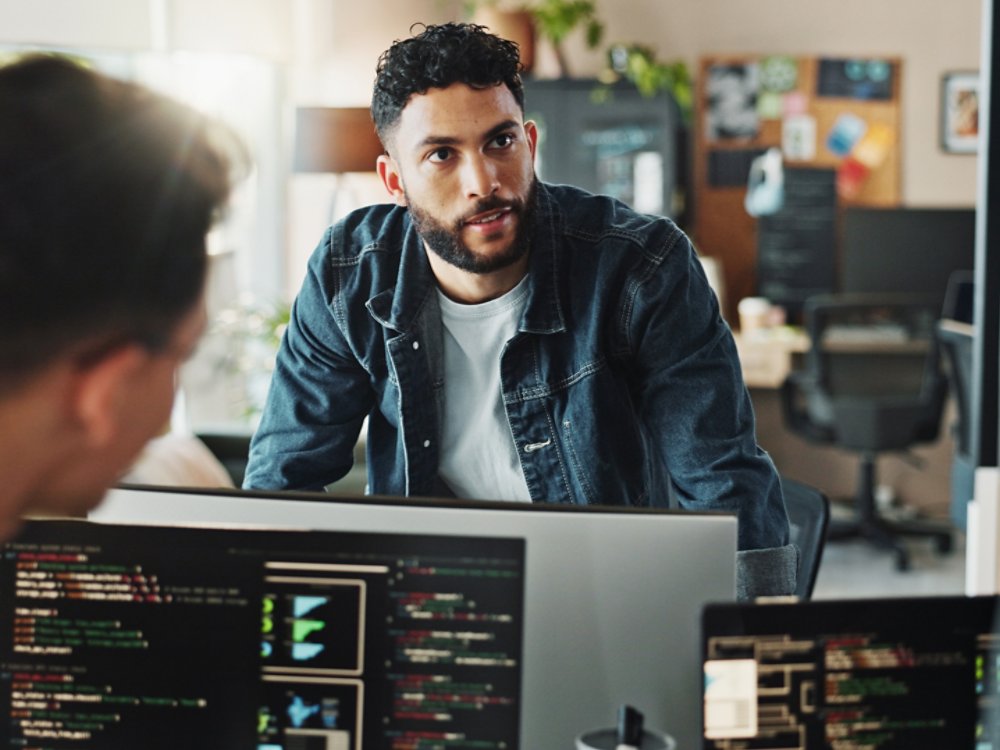 Men, discussion and meeting with computer for coding solutions, problem solving or ideas at office. Male people, designers or developers working on technology for software development at workplace.