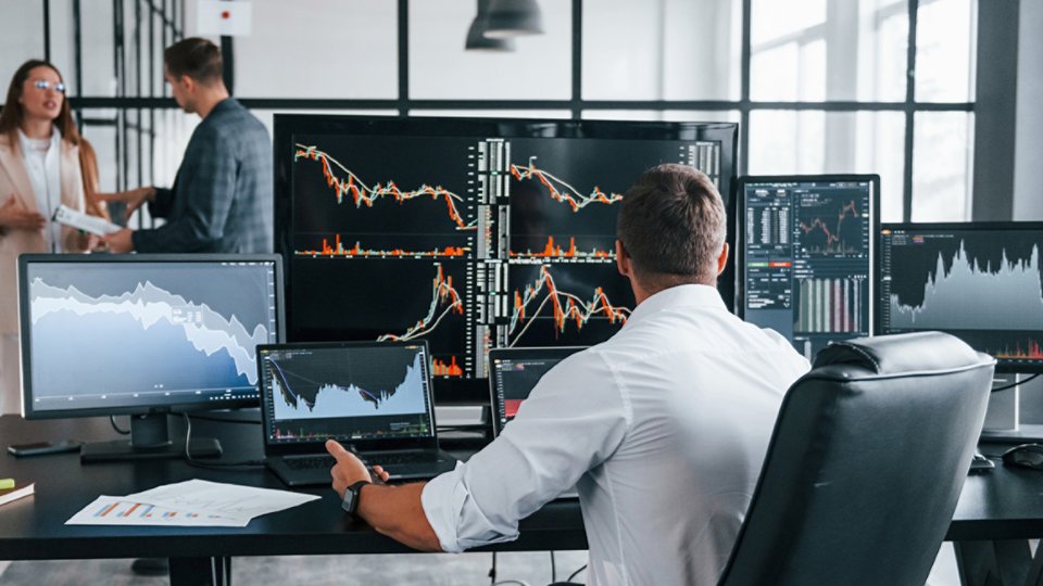 Man at workstation with multiple screens showing data