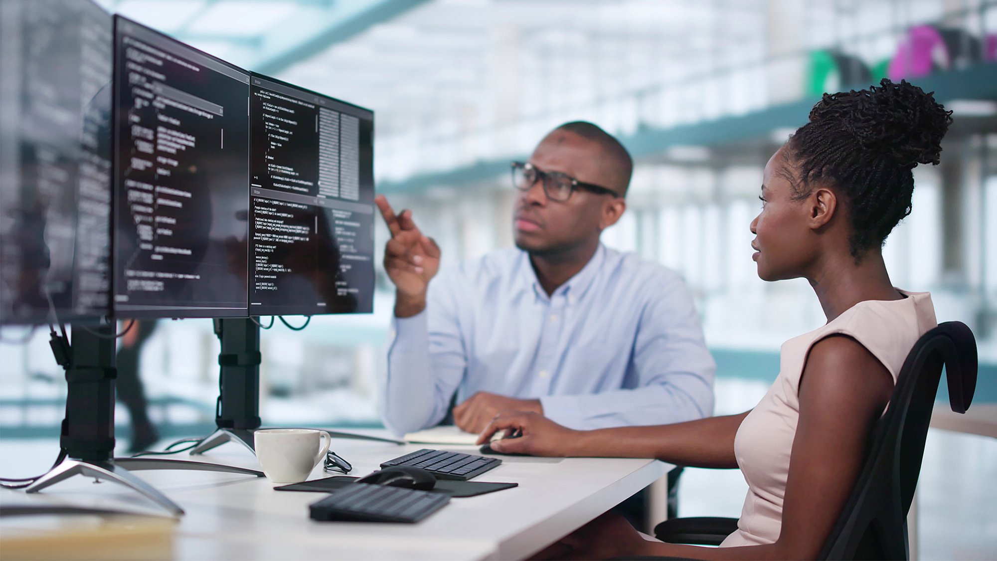man woman examine code on multiple screens