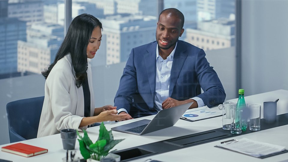 man woman looking at laptop with view of downtown in background