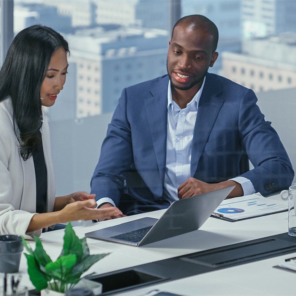 man woman looking at laptop with view of downtown in background