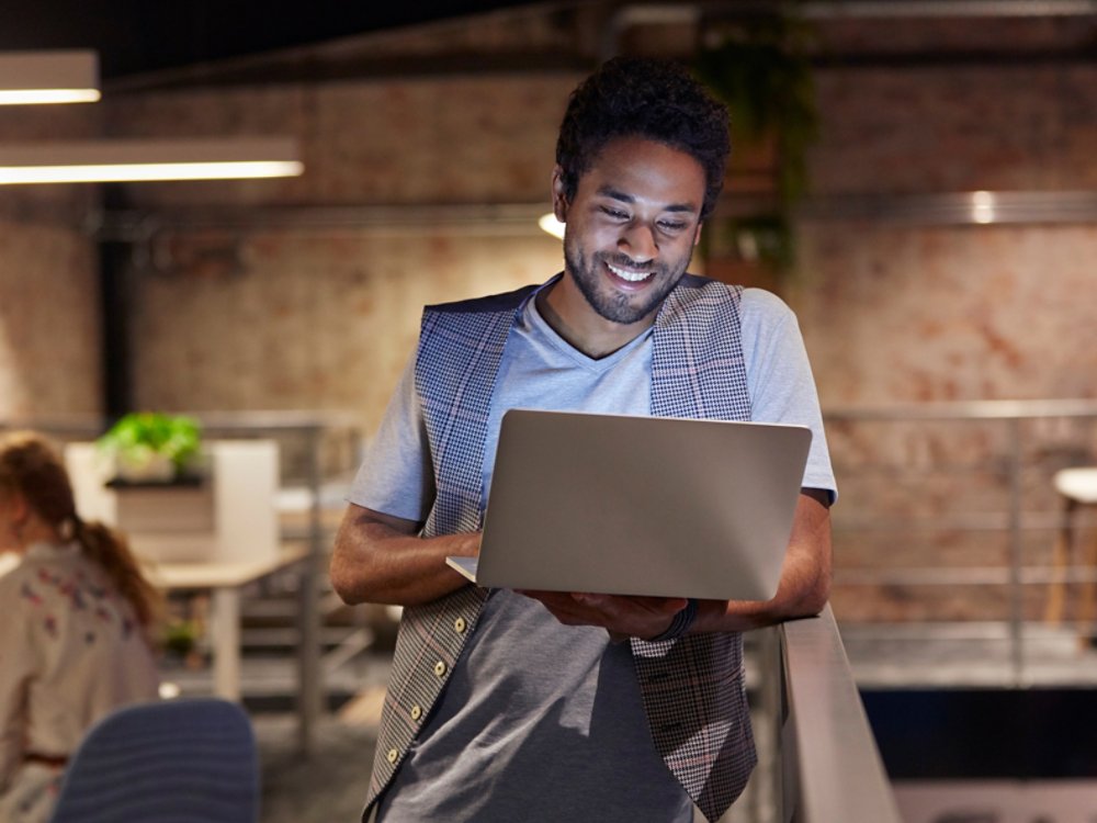 man smiling while working on a laptop 16x9