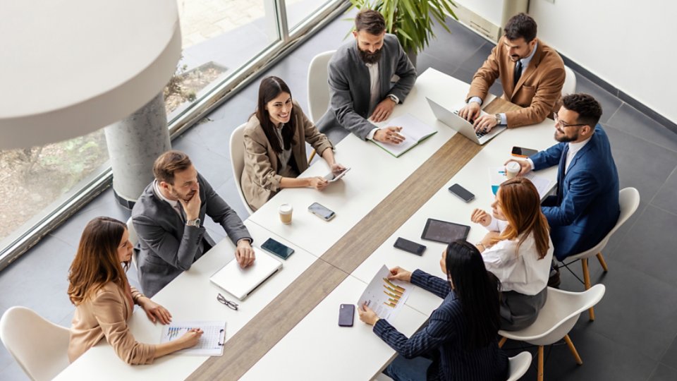From above view of leadership team sitting and conference table at boardroom and having meeting.