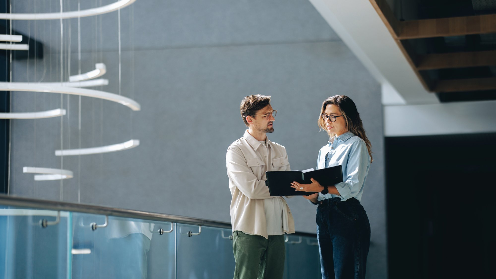 Two business partners, male and female, have a detailed discussion as they review a document together. Professional business people negotiating the terms of their partnership in an office.