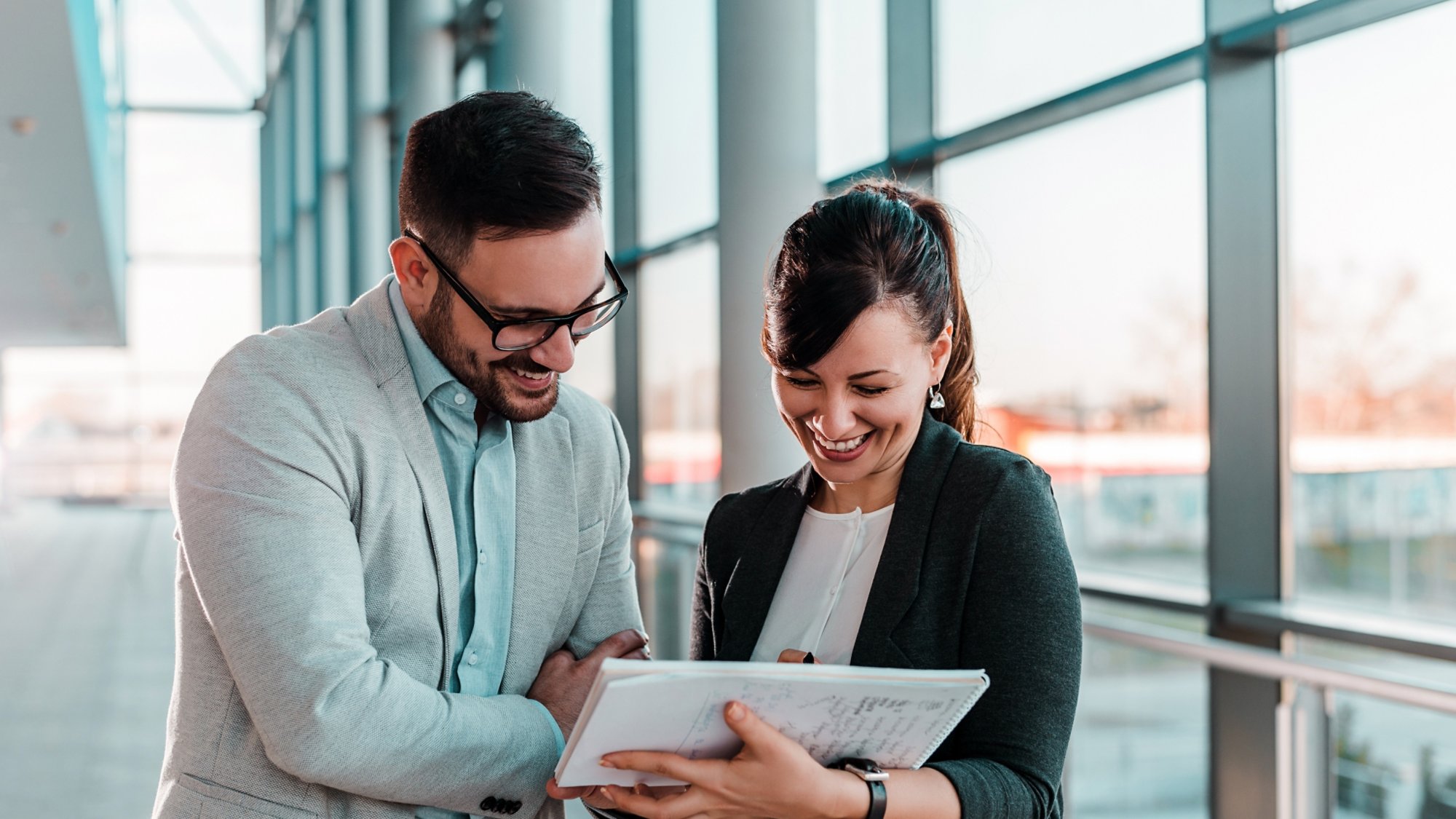 Attractive business people having meeting in office hall near window.