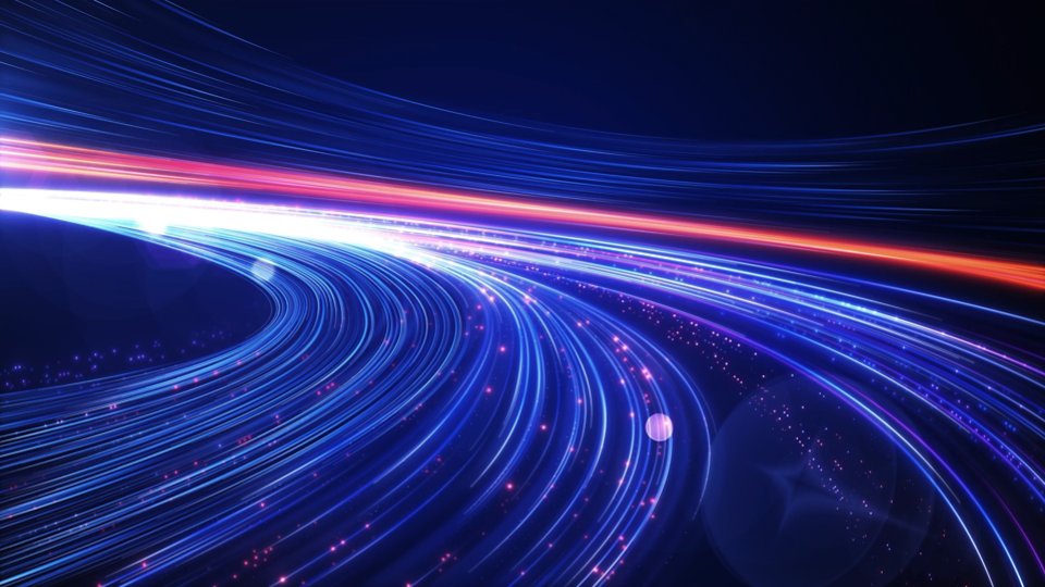 Abstract blue and red light trails curve across a dark background, suggesting high-speed motion and digital connectivity. The scene resembles a futuristic highway or data stream with glowing particles scattered along the paths. Bright neon lines create a sense of depth and perspective, converging toward the distance. Overall, the image conveys technology, speed, and modern innovation.