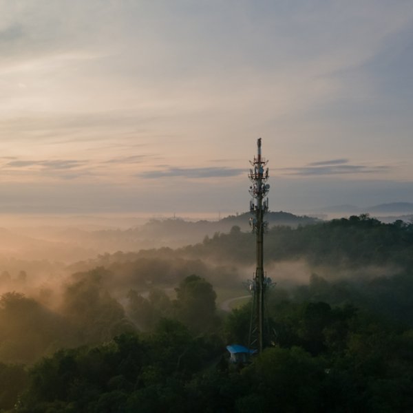 Aerial view of Communication tower during morning sunrise with clouds, mists and fog