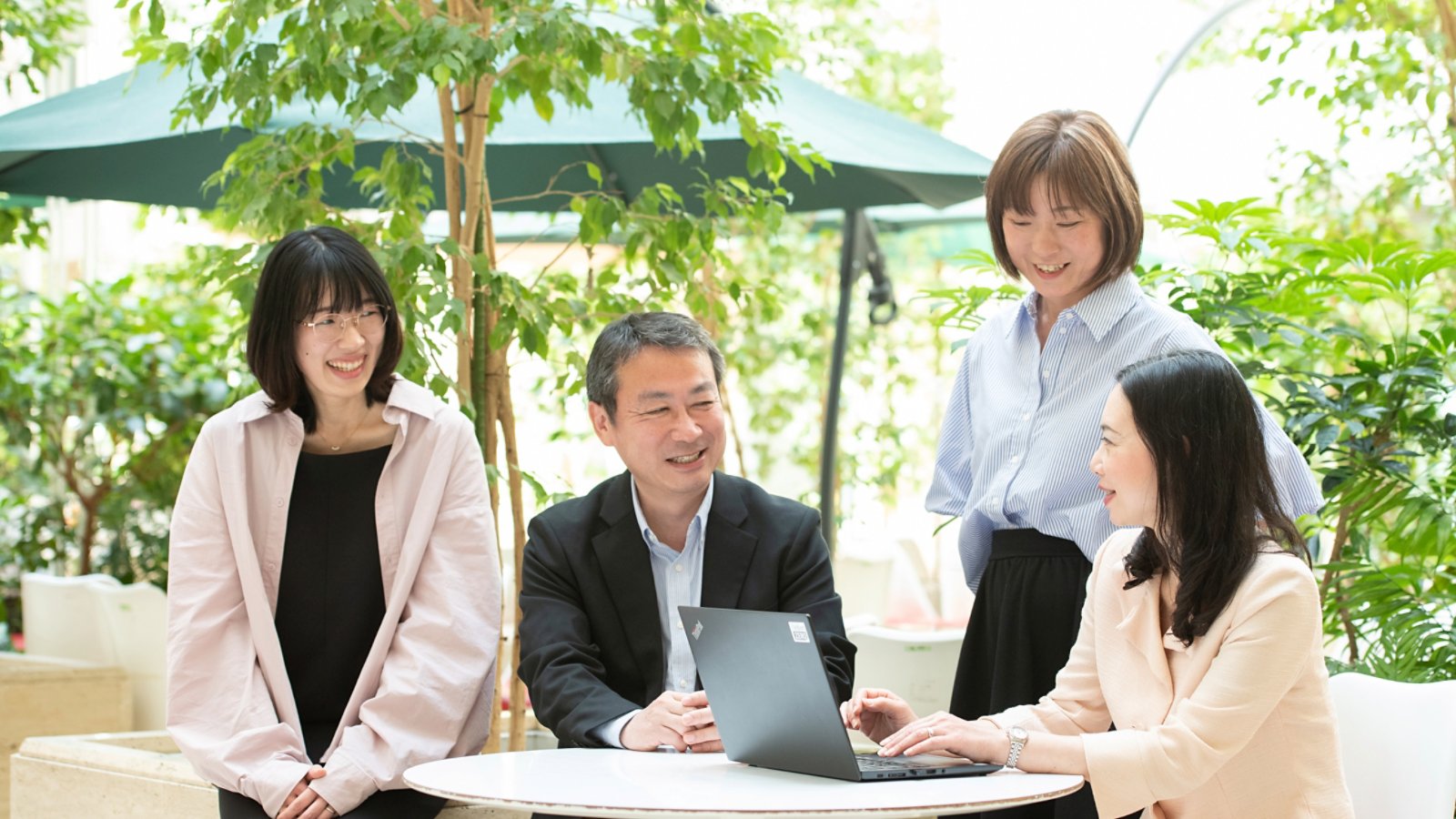 Four people sitting around woman with laptop