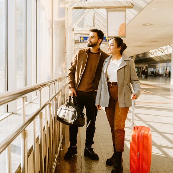 Young indian couple looking in window together at airport indoors