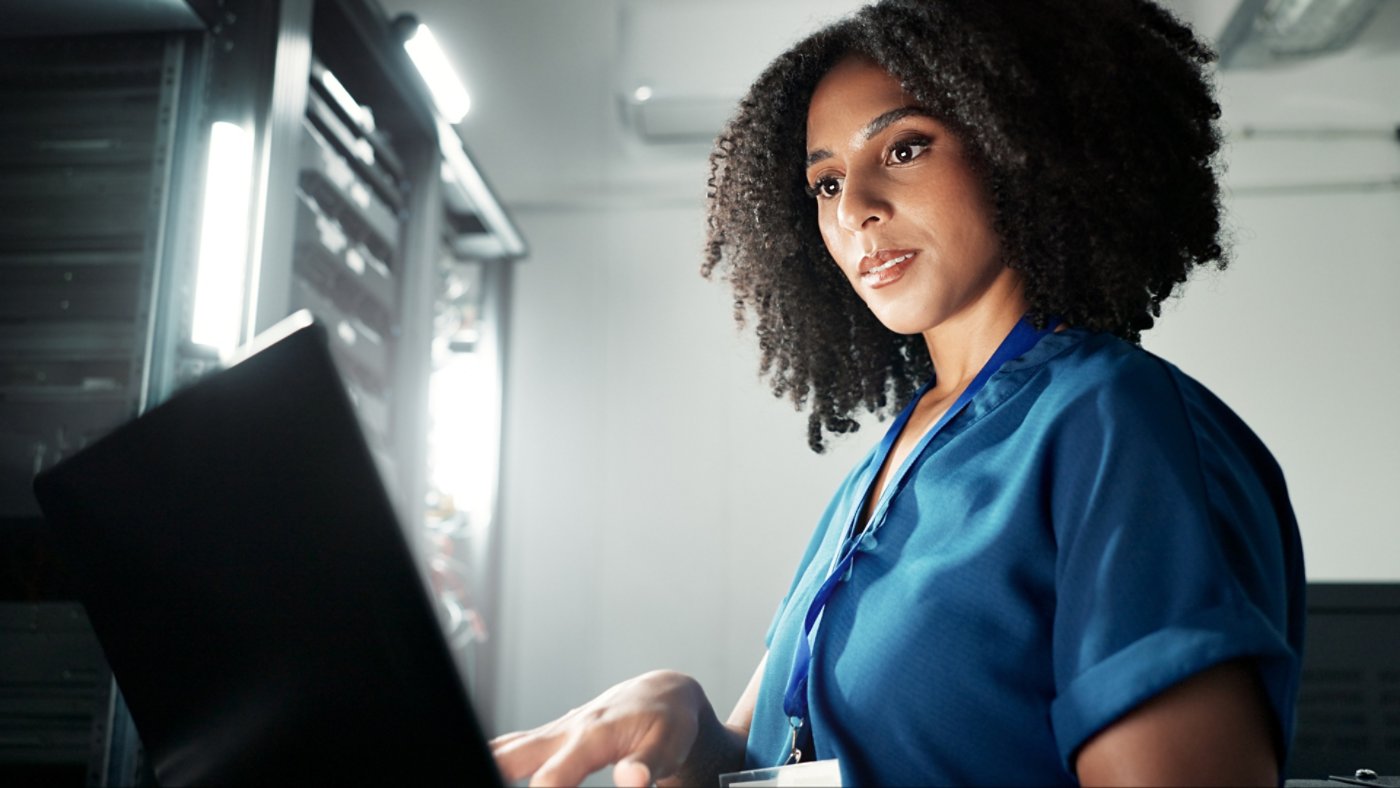 Computer, server room and woman programming software, update or system network maintenance. Technology, data center or technician on laptop for information, cyber security or code for cloud computing.