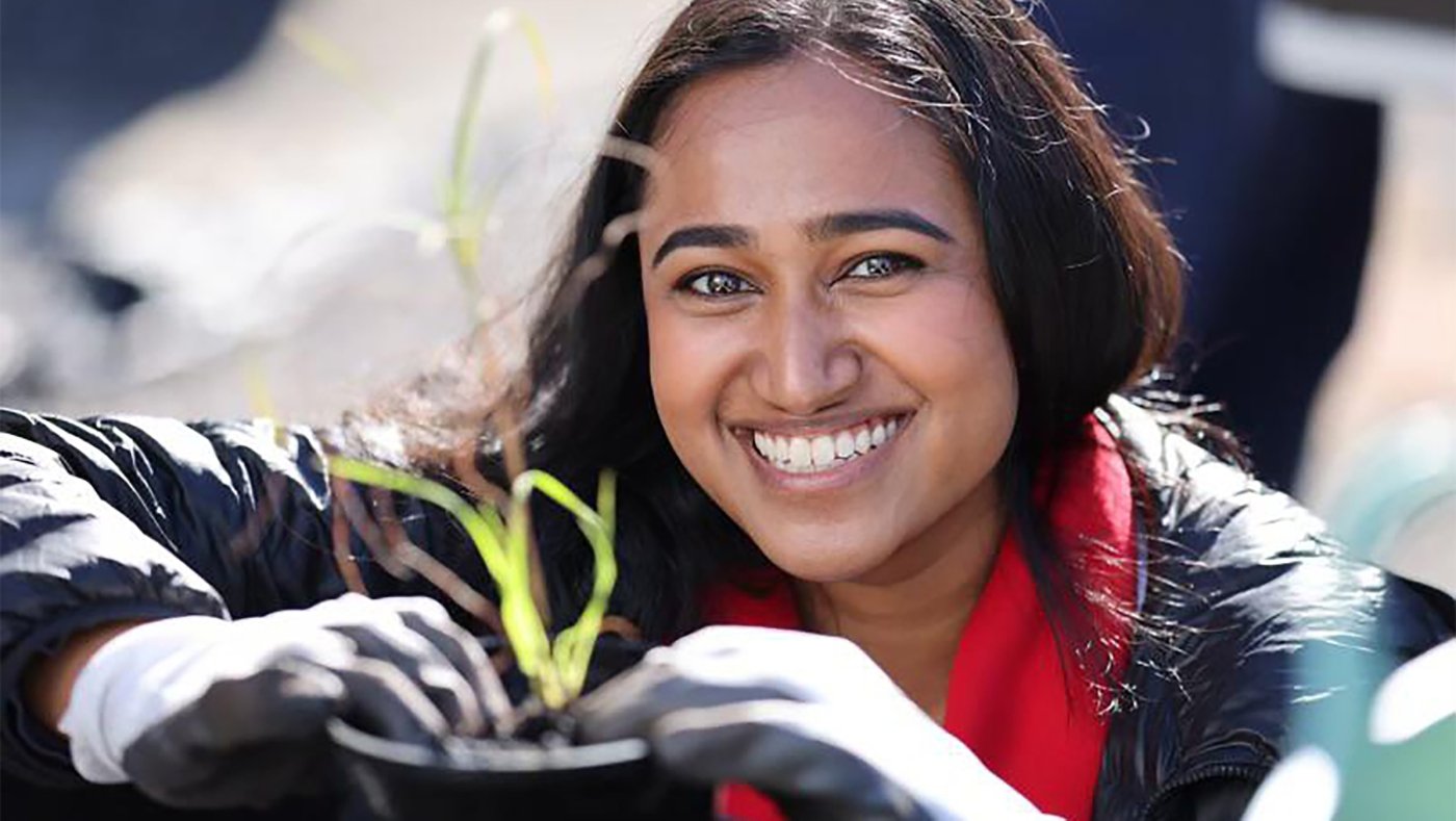 Woman smiling at One Tree Planted Event in Australia while taking care of a small plant or possibly a sapling
