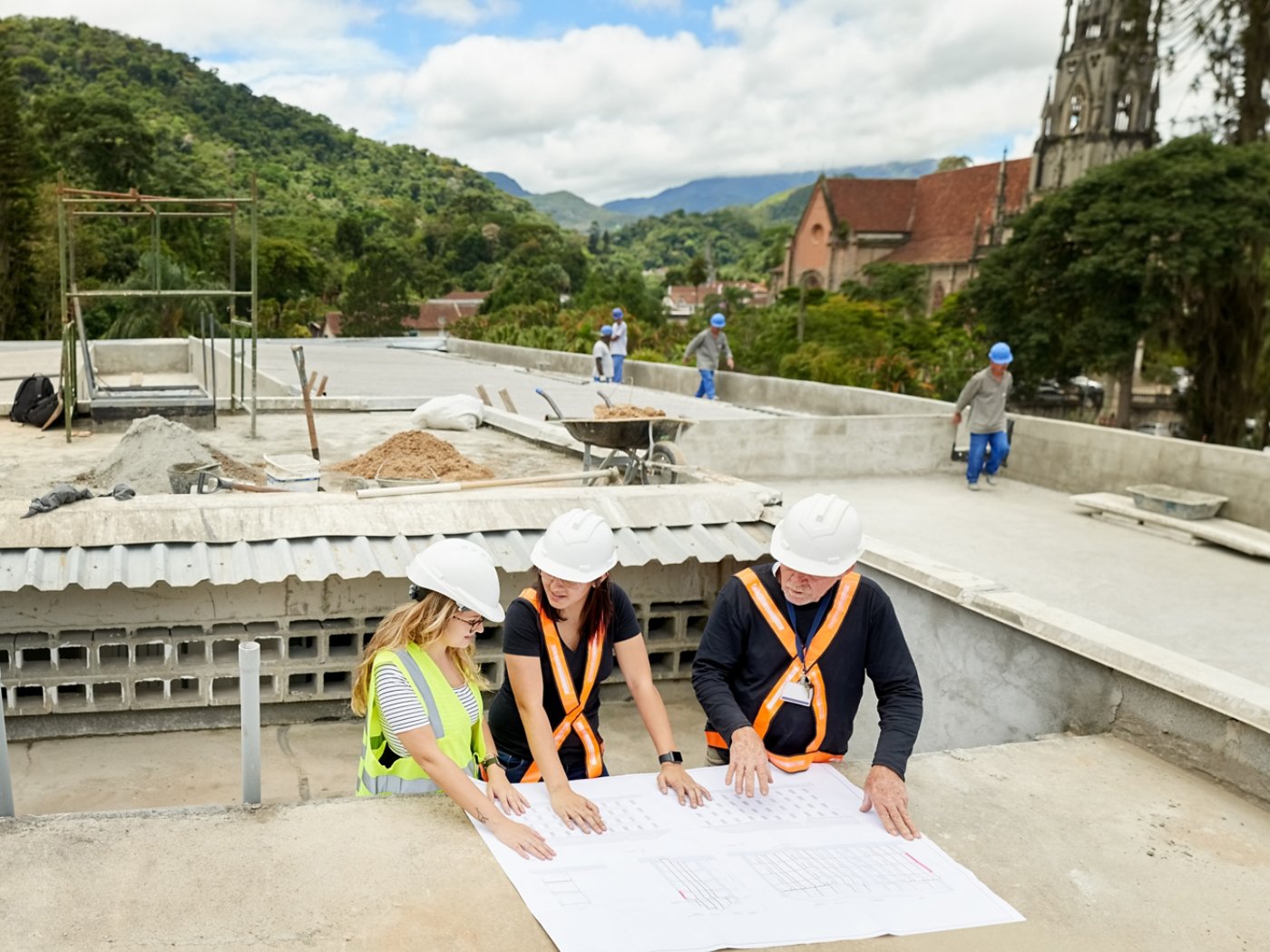 Shot of construction workers and architect  reviewing blueprint at construction site