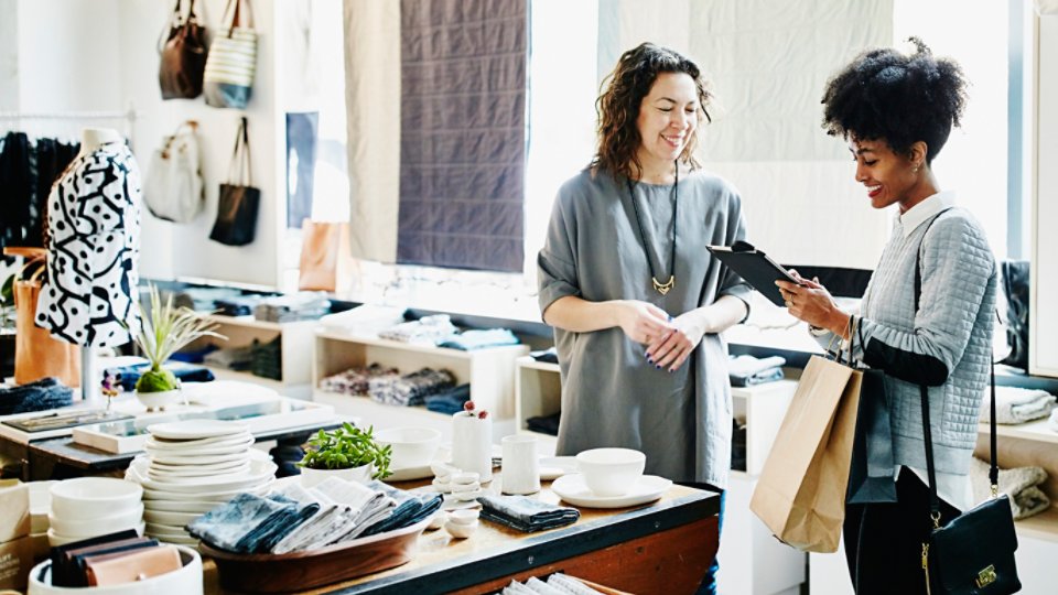Smiling customer completing transaction on digital tablet in boutique shop