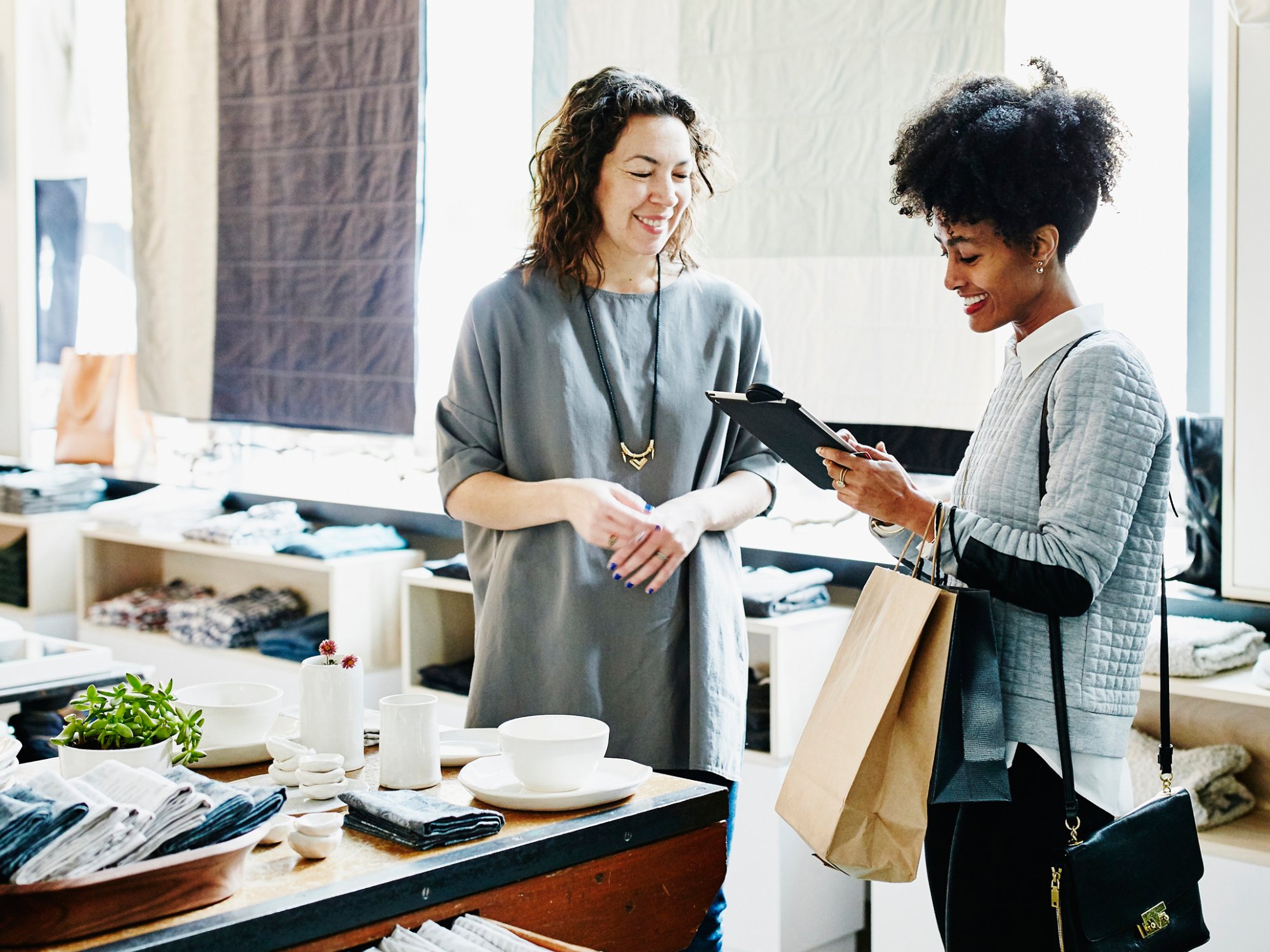 Smiling customer completing transaction on digital tablet in boutique shop