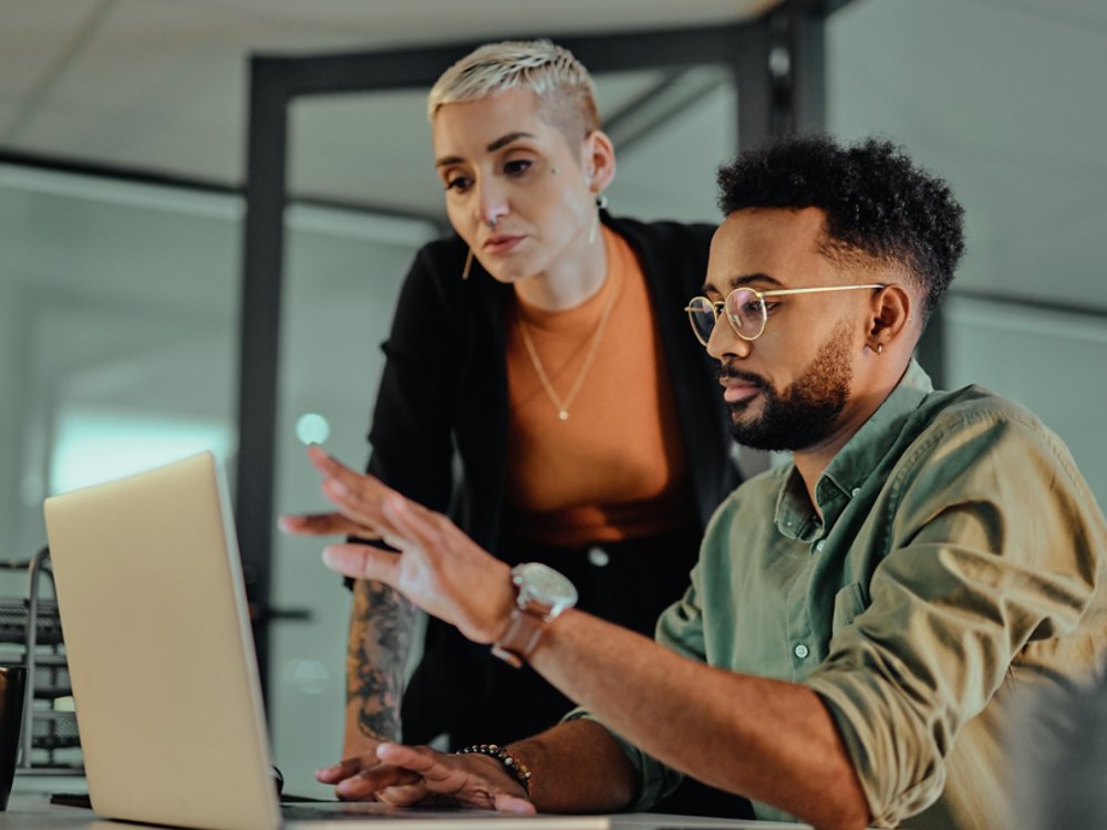 Shot of two young designers working together on a laptop in an office at night