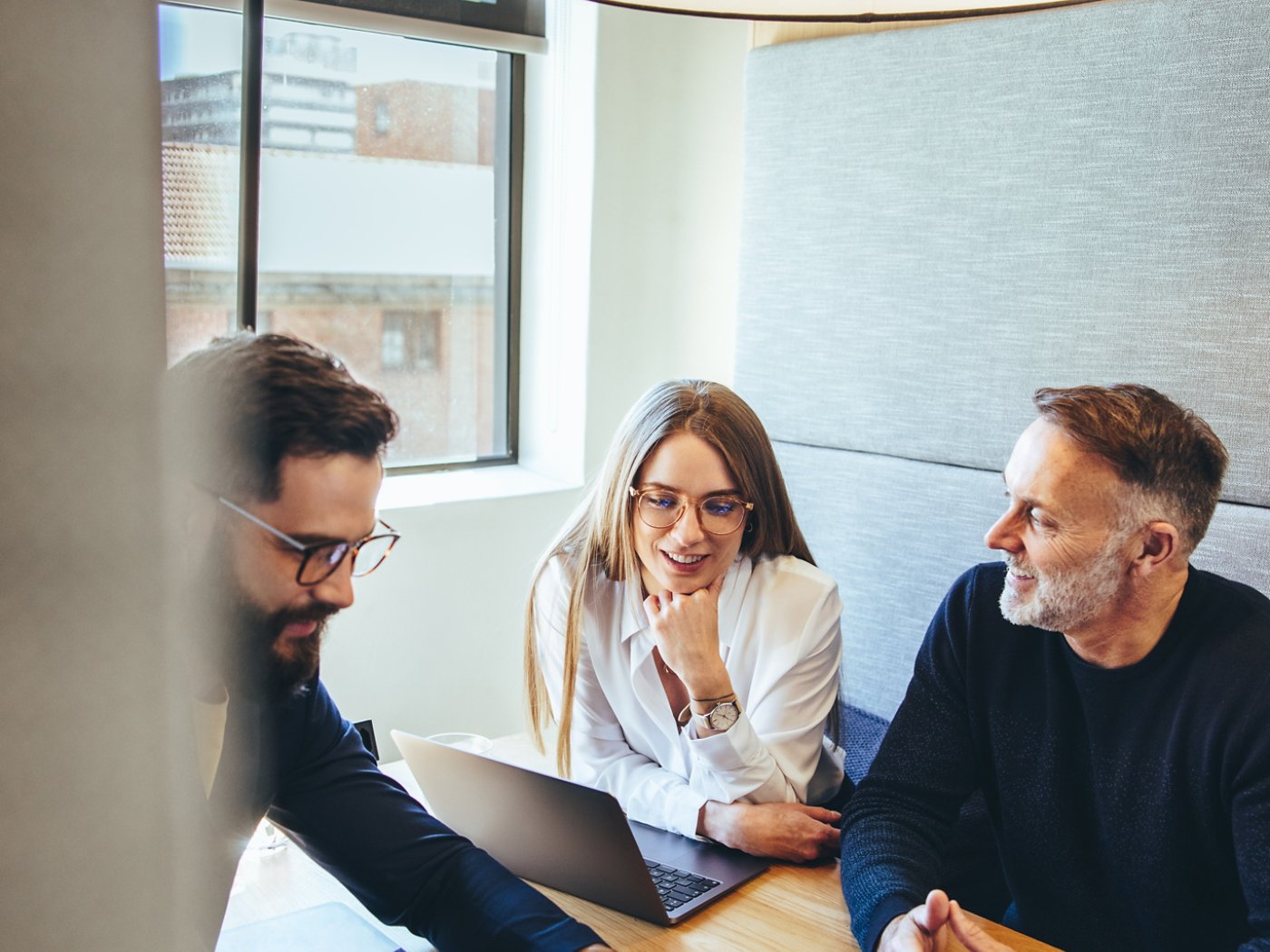 Happy businesspeople working in a modern co-working space. Three business colleagues smiling while having a discussion. Team of diverse entrepreneurs collaborating on a new project.