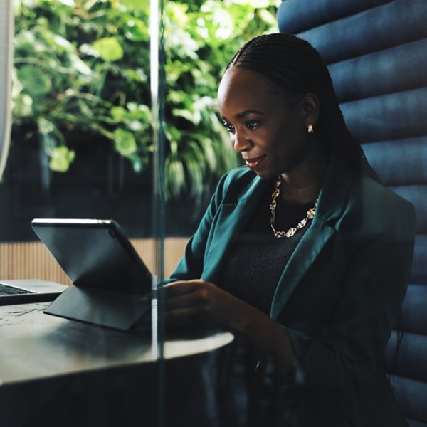 Tablet, office and businesswoman in cubicle for company budget review and accounting news. Technology, hybrid work booth and African financial manager with online investment report or reading update.